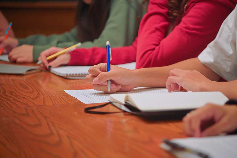 A row of Students Writing in Notebooks