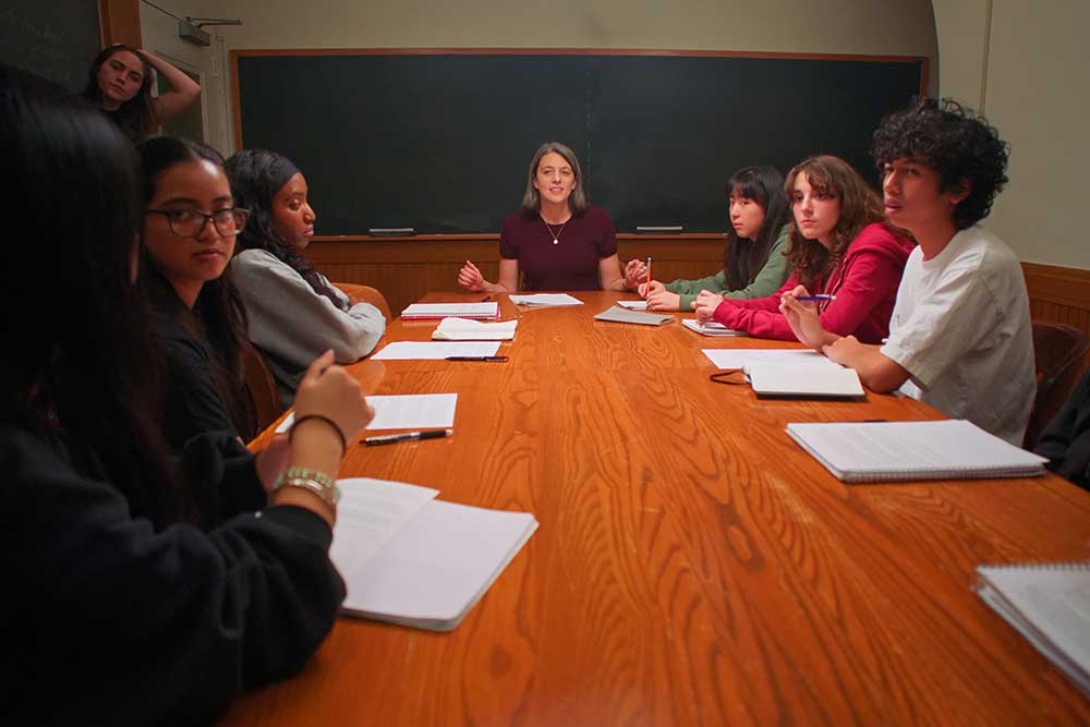 Students gather around a seminar table with a professor at the head.